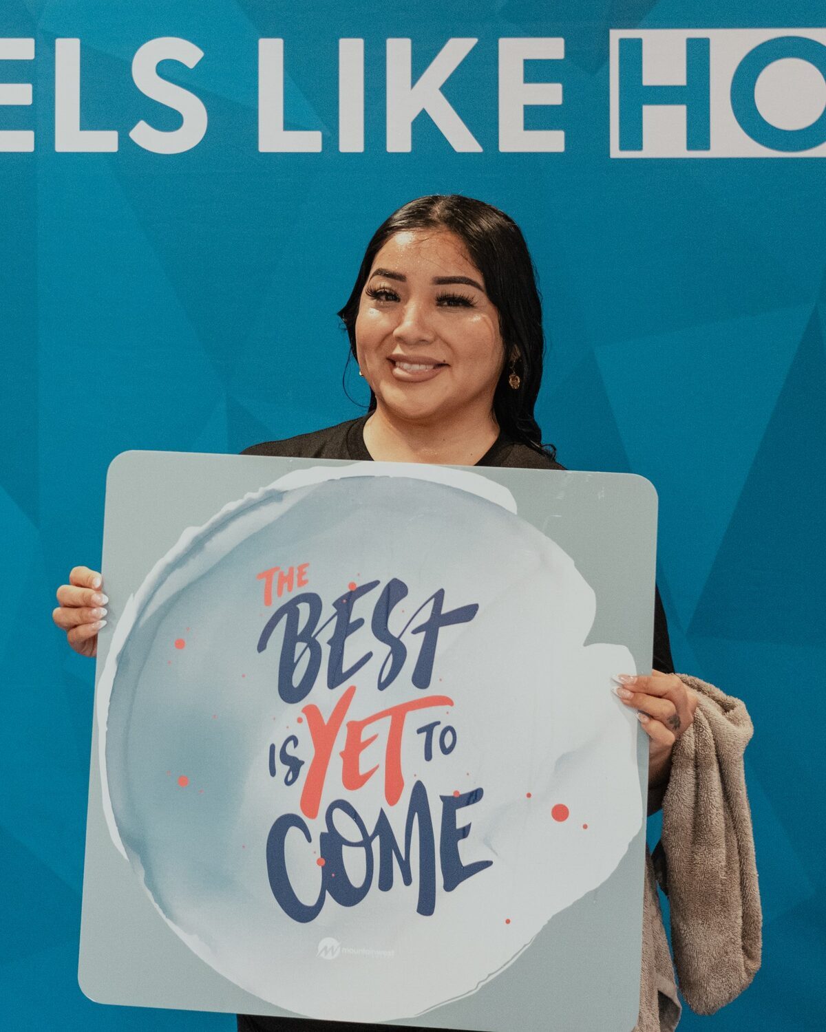 A young woman holding a sign reading The best is yet to come