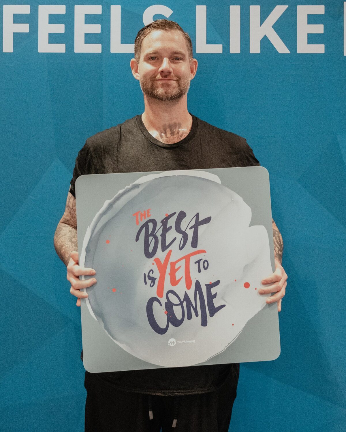 A man holding a sign reading The best is yet to come