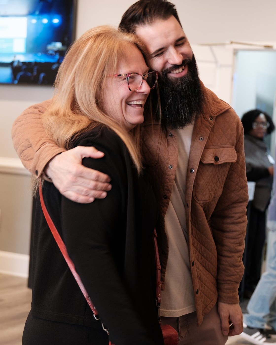 Two people laughing in a hug in the Lilburn lobby after the Gathering