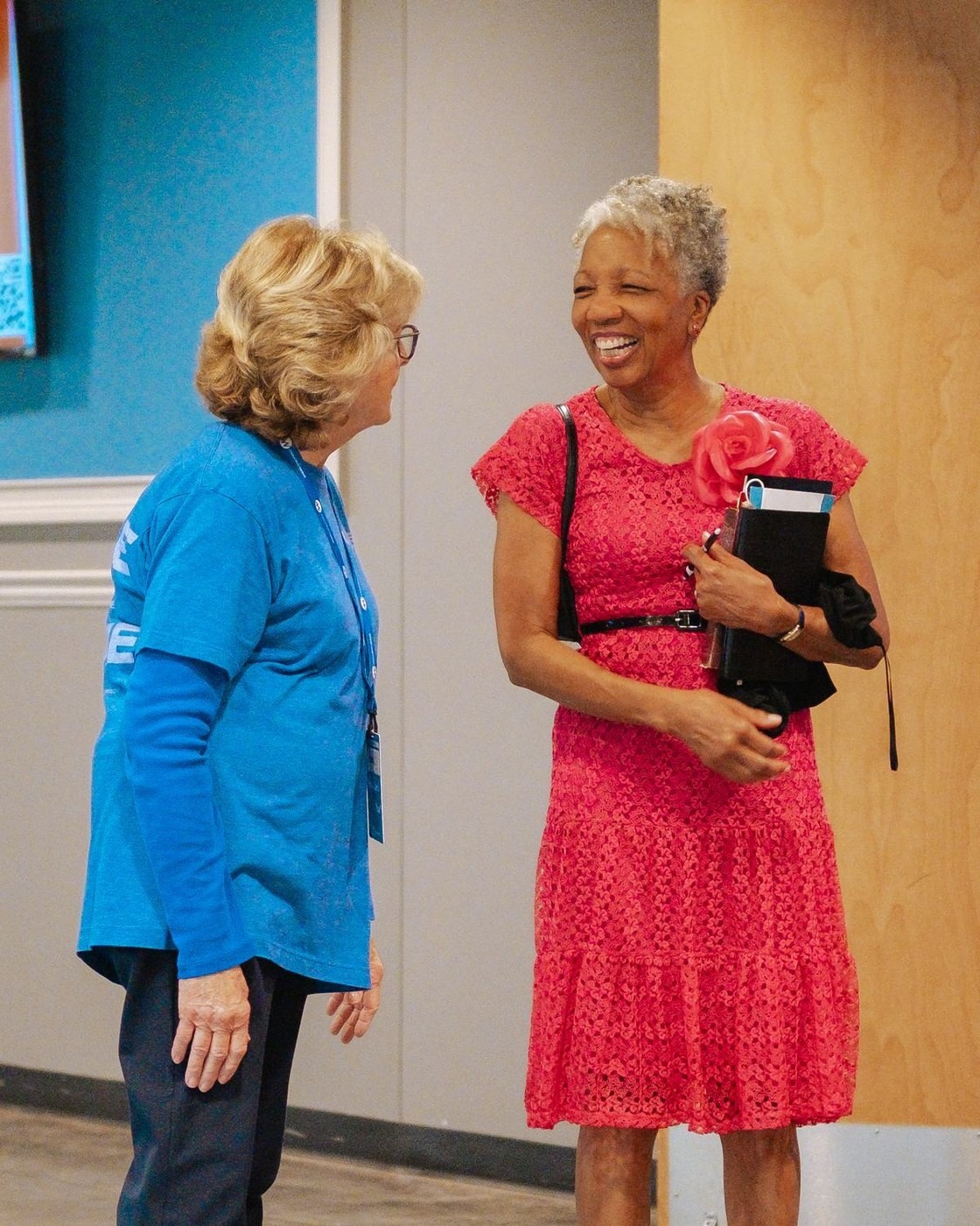 A guest laughing with a volunteer in the Tucker lobby before the Gathering