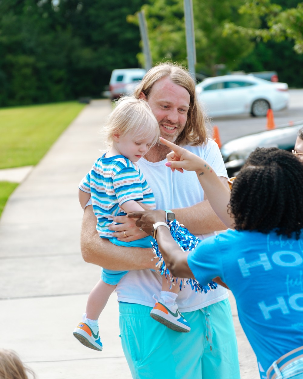 A dad carrying his young son toward the doors at Chamblee as a Hope Team volunteer reaches out to greet them