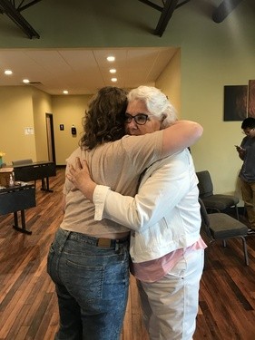 Picture of 2 women hugging in the church lobby.