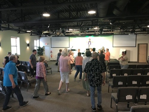 Picture of the church sanctuary with all of the congregants walking up to the front to pray over someone.