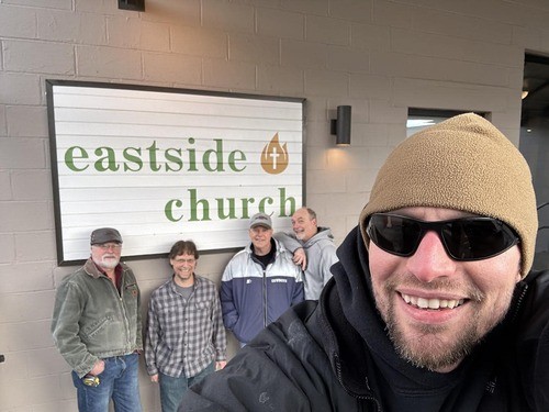 Picture of 5 men smiling, standing in front of the Eastside Church sign in front of our building.