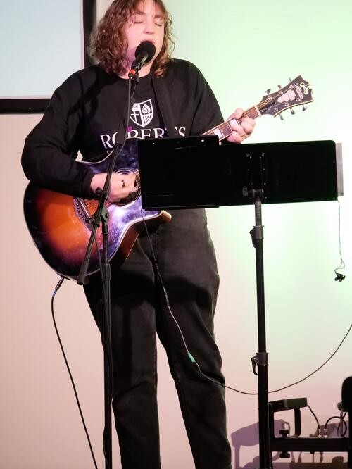 Picture of a woman leading worship and playing guitar
