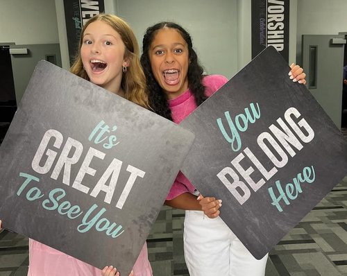 Two teen girls holding signs saying, 