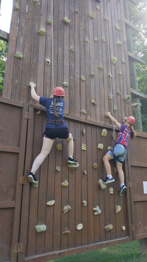 Two girls climbing the rock wall