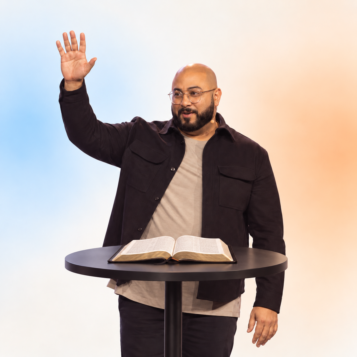 Joe Cameneti Jr behind a black high-top table with an open Bible