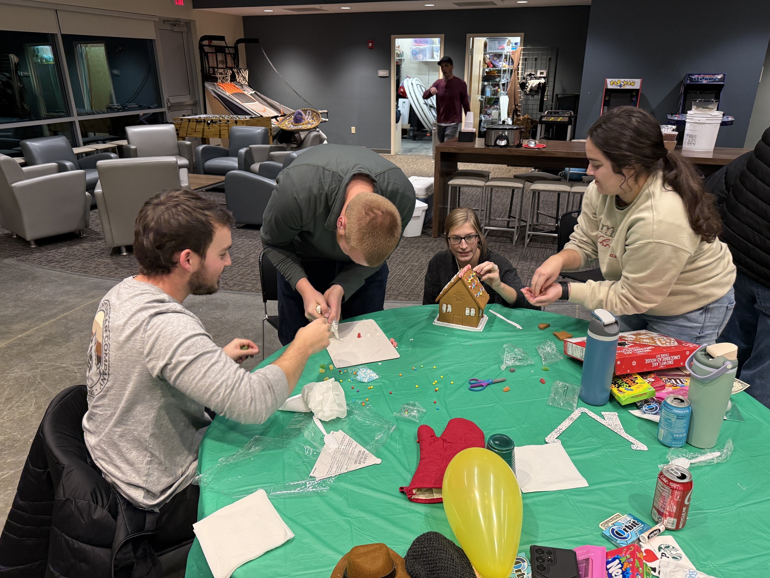 Young adults building a gingerbread house together