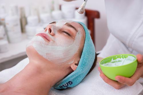 Woman laying down and receiving a white cream face mask.